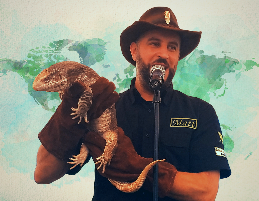 image shows Matt Gabriel, a white man with a beard and an outdoorsy kind of hat, holding what I think is probably a komodo dragon