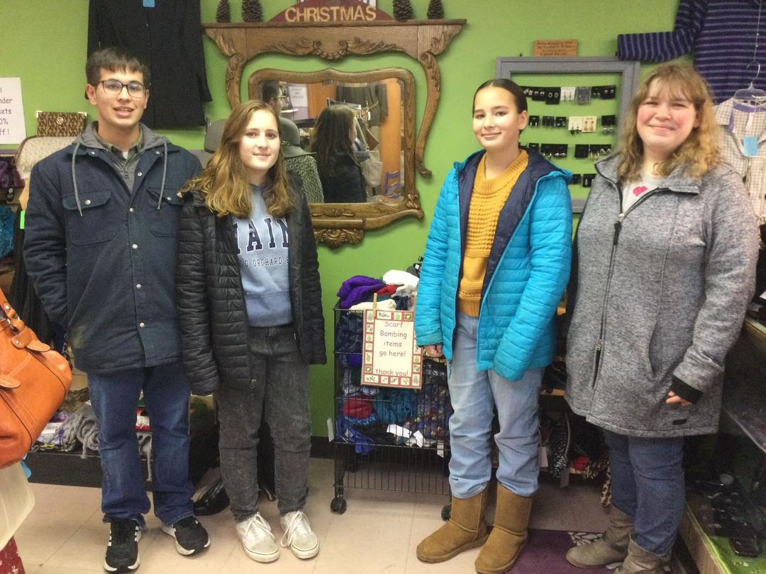 Teens standing in front of collection bins at local business. 