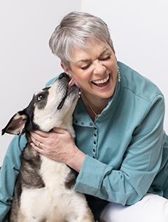 picture of Kristan Higgins, a white woman with short hair, and her black and white dog