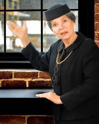 Jarice Hanson performing as Frances Perkins in black suit and veiled hat