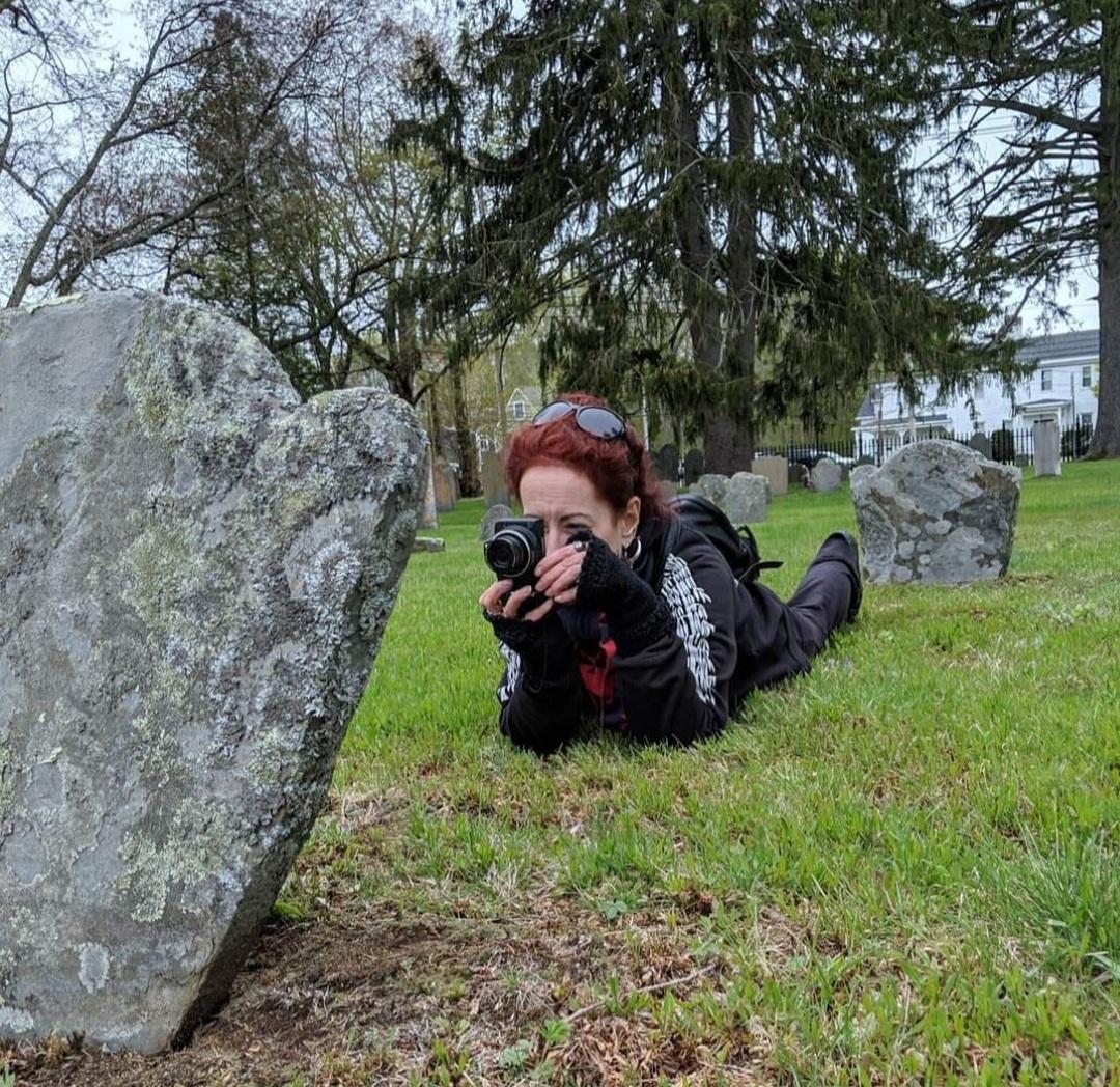 a woman photographing a gravestone