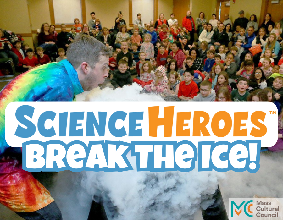 image shows a person wearing a rainbow tie-die lab coat, over a table covered in a dry ice cloud, with an audience of children watching